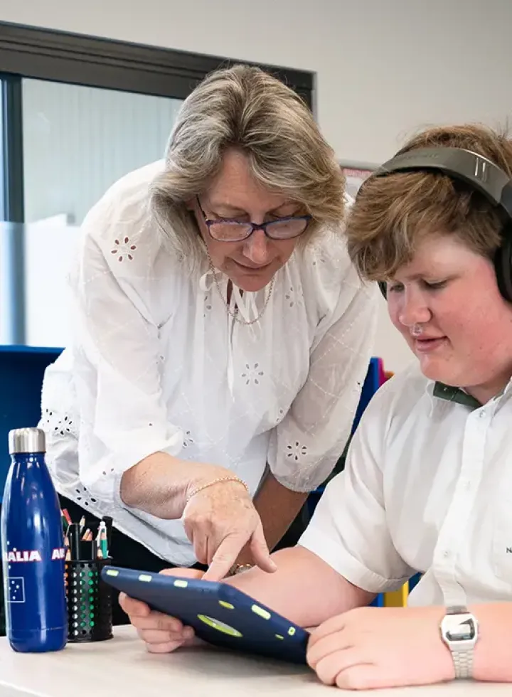 Teacher helping student with task on iPad at New Hope Christian School