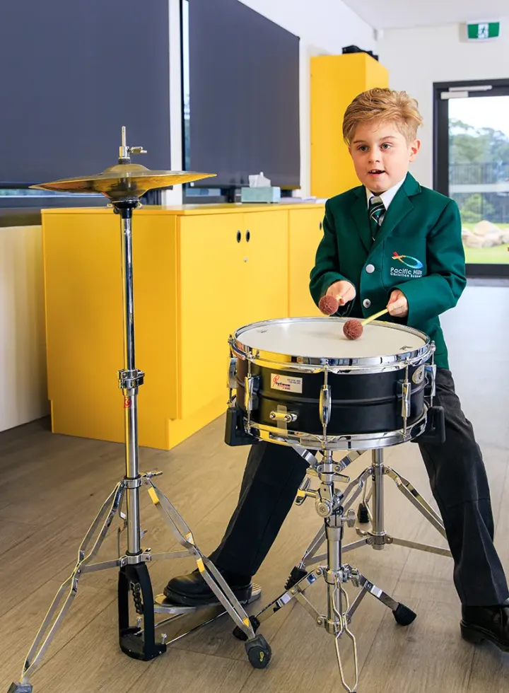 Junior school student playing drums in music class at New Hope Christian School
